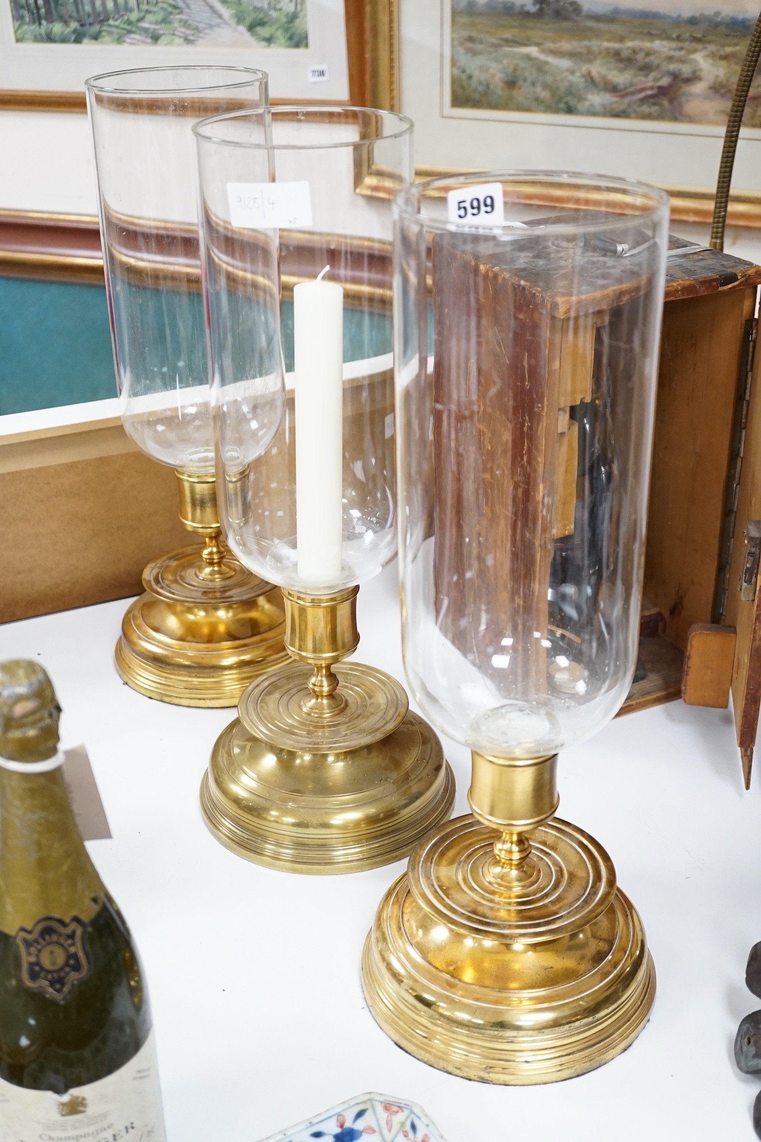 Three matching brass and glass storm lanterns, 49cms high